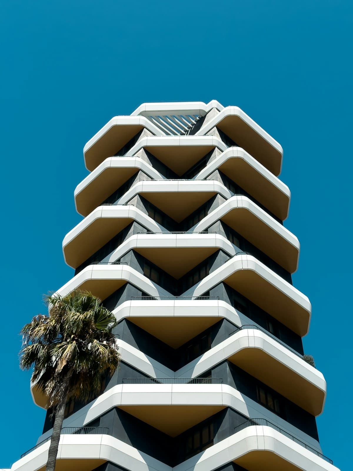 Edifício de habitação em Lisboa com varandas geométricas e uma palmeira